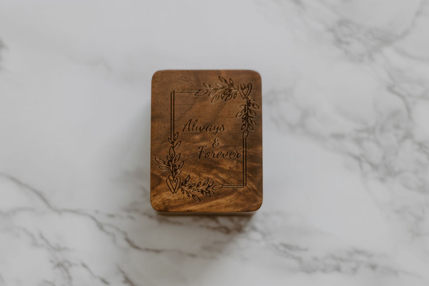 Vintage brown leather book cover with ornate floral embossing rests on white marble surface.