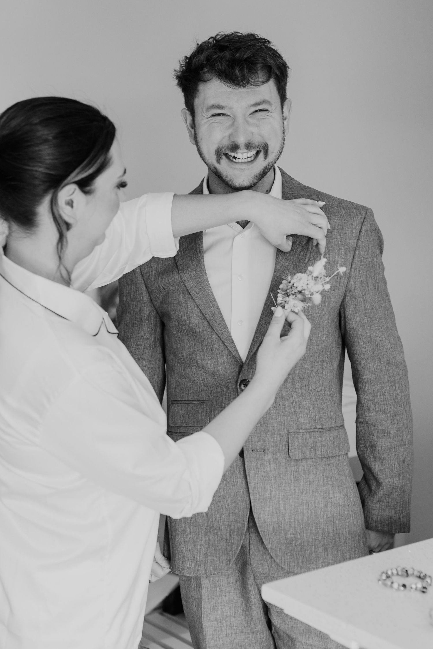 Candid moments of laughter and joy captured in black and white during wedding preparations.