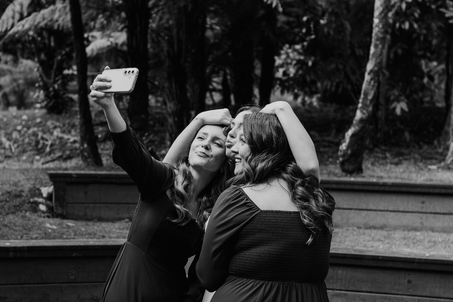 Two people in black taking a selfie together outdoors in a black and white photograph.