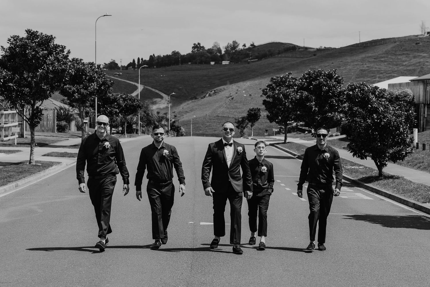 Group of military personnel walking in formation along a paved path at a training facility.