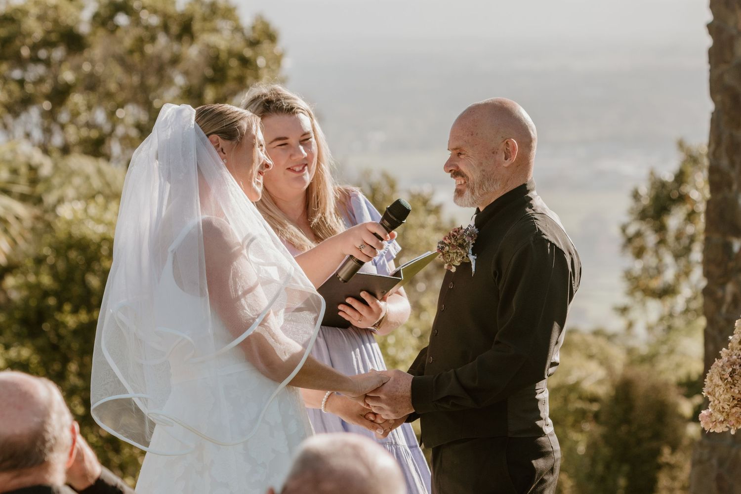 A couple share an intimate dance together during their wedding celebration as sunlight filters through trees.