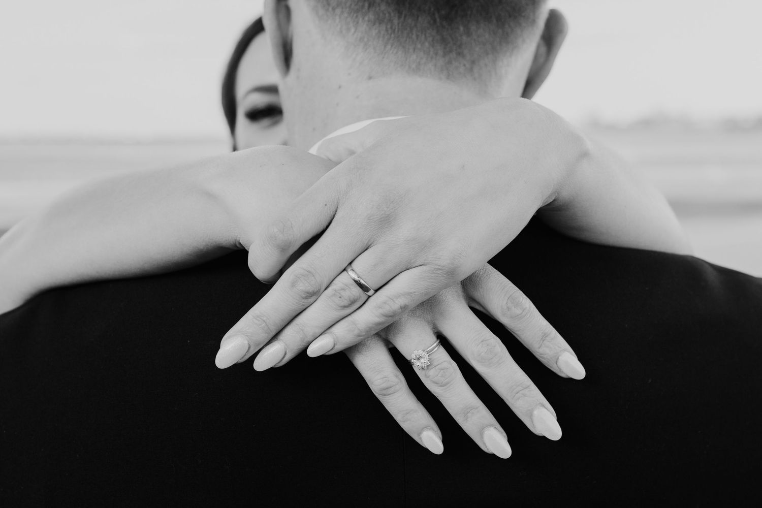 Black and white detail shot of overlapping hands on textured fabric.