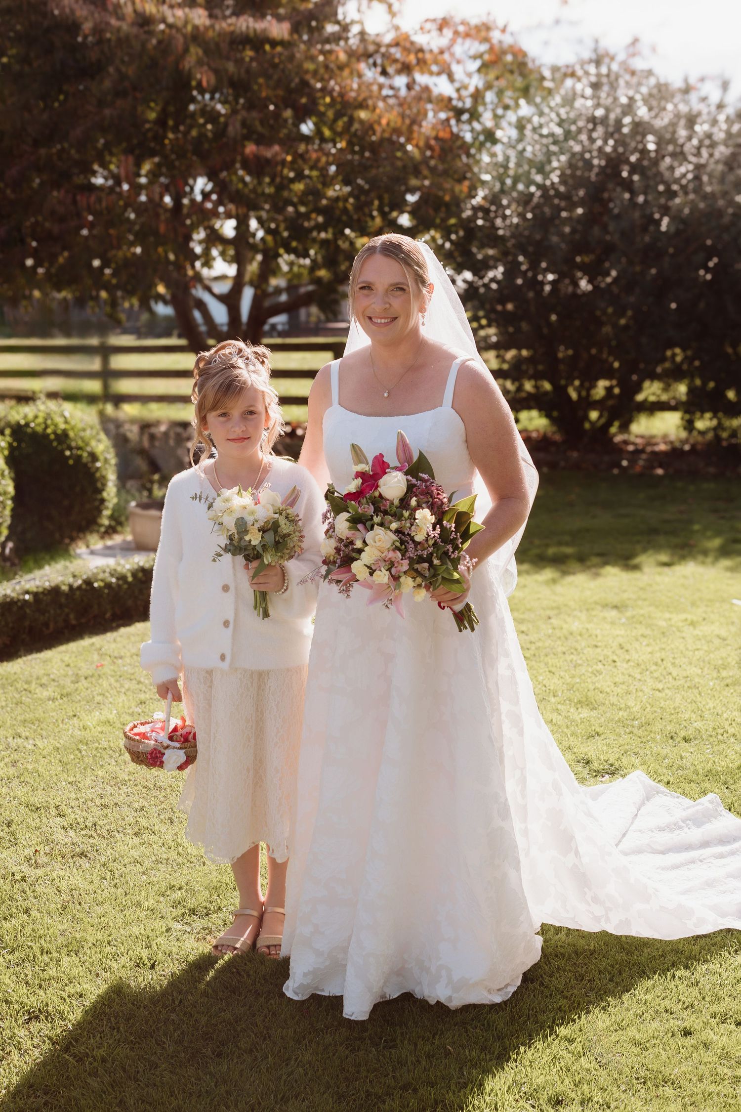 Wedding ceremony in a sunny garden setting with white dresses and pink floral bouquets on a beautiful autumn day.