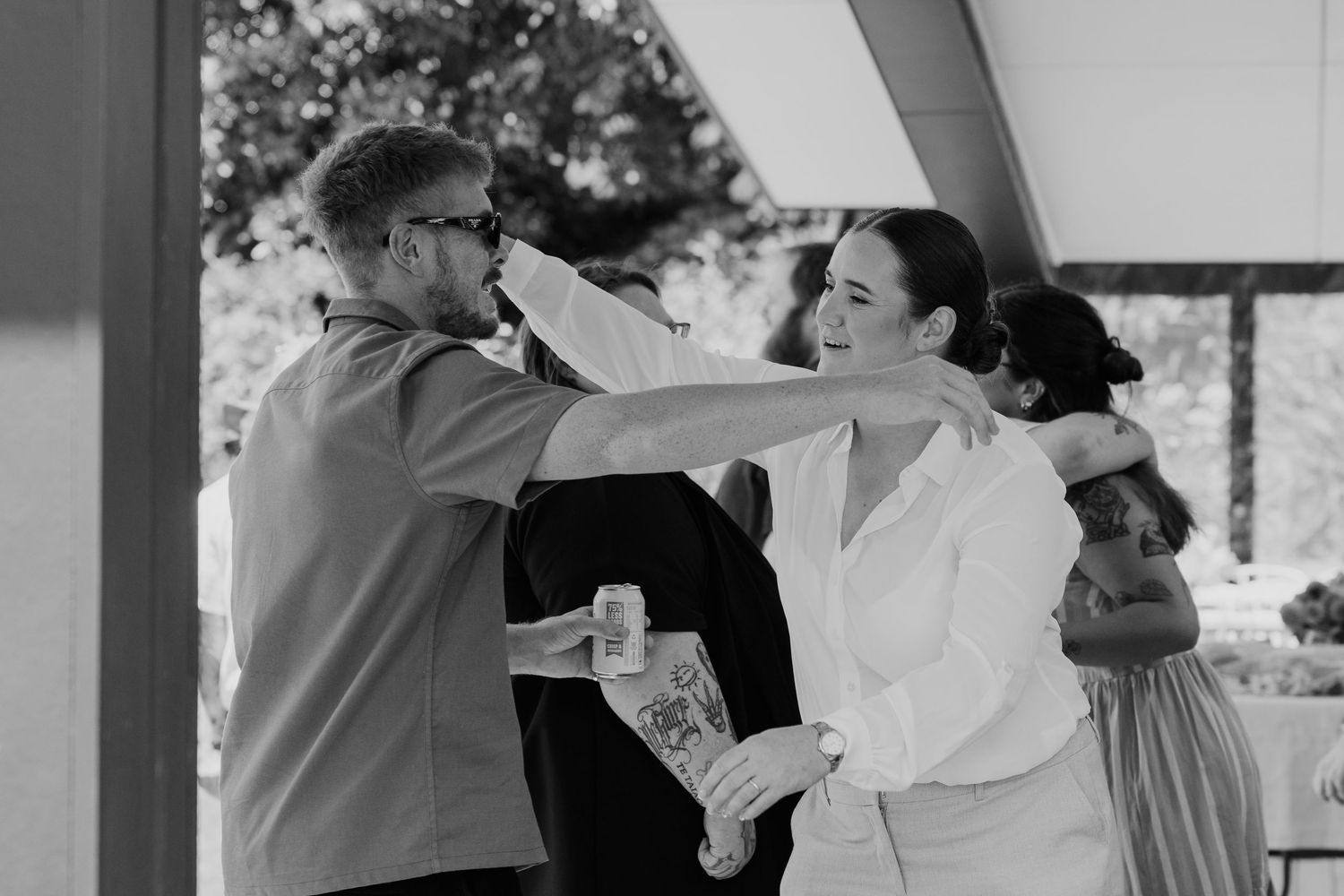 Black and white photo of guests helping bride prepare at wedding venue.
