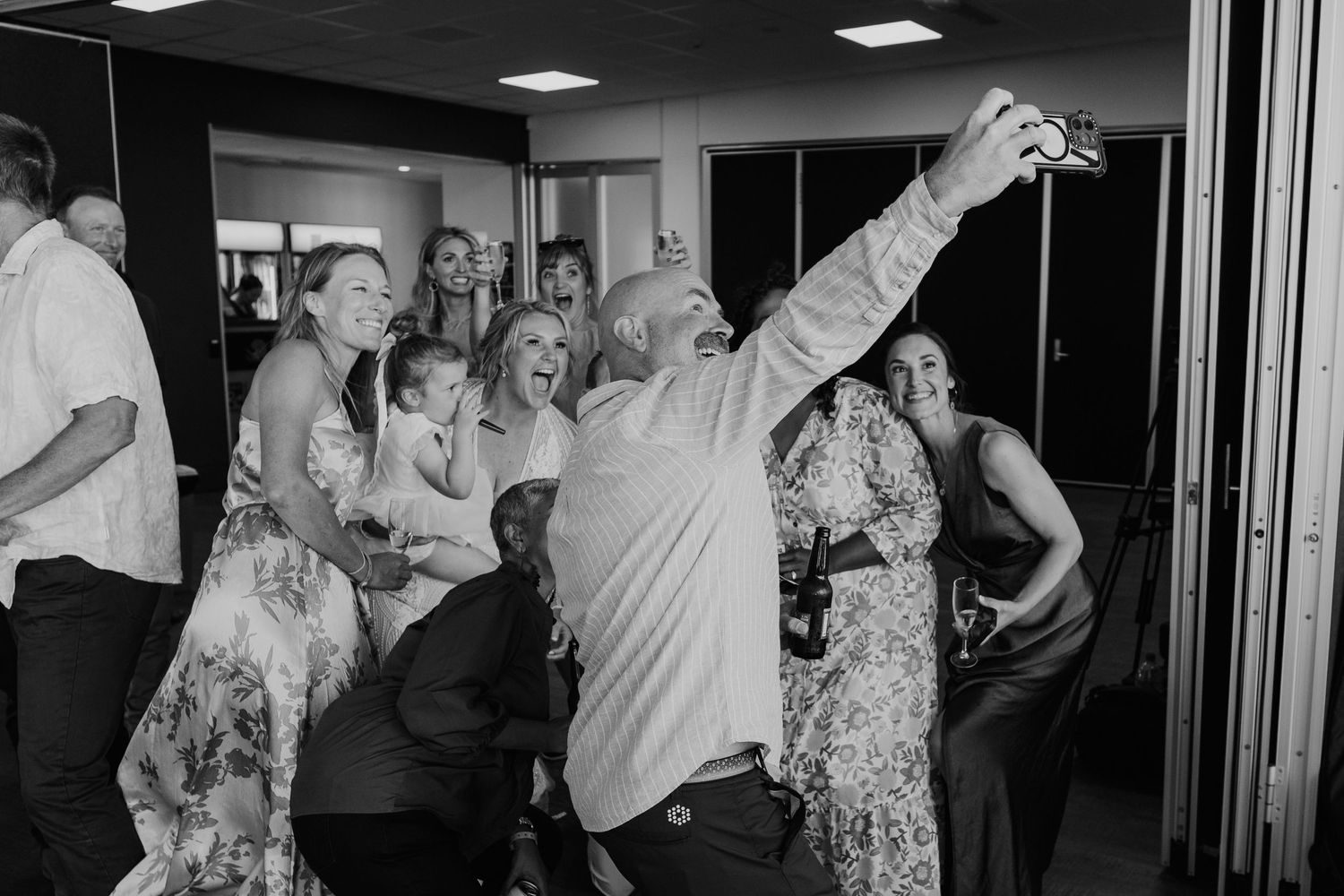 People dancing and celebrating enthusiastically at what appears to be a wedding reception in black and white. Papamoa Surf Lifesaving Club