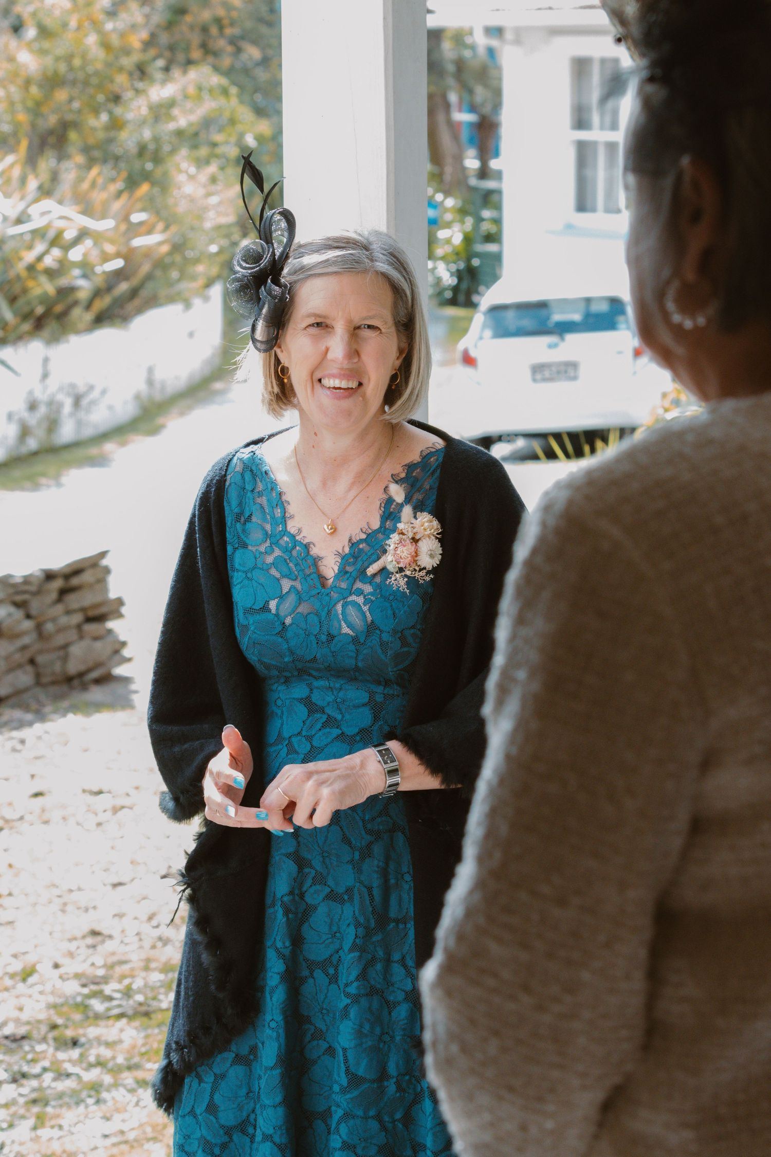 A guest in a teal lace dress enjoys conversation at a wedding reception.