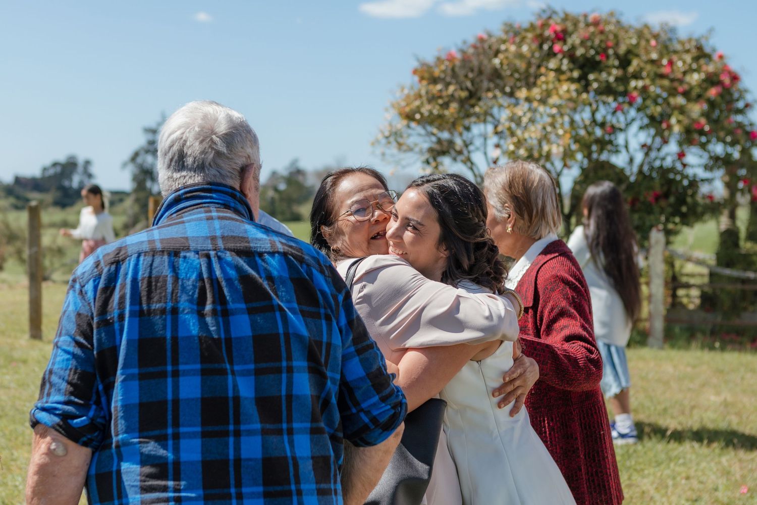 Wedding guests gather outside on a sunny day near a church building.