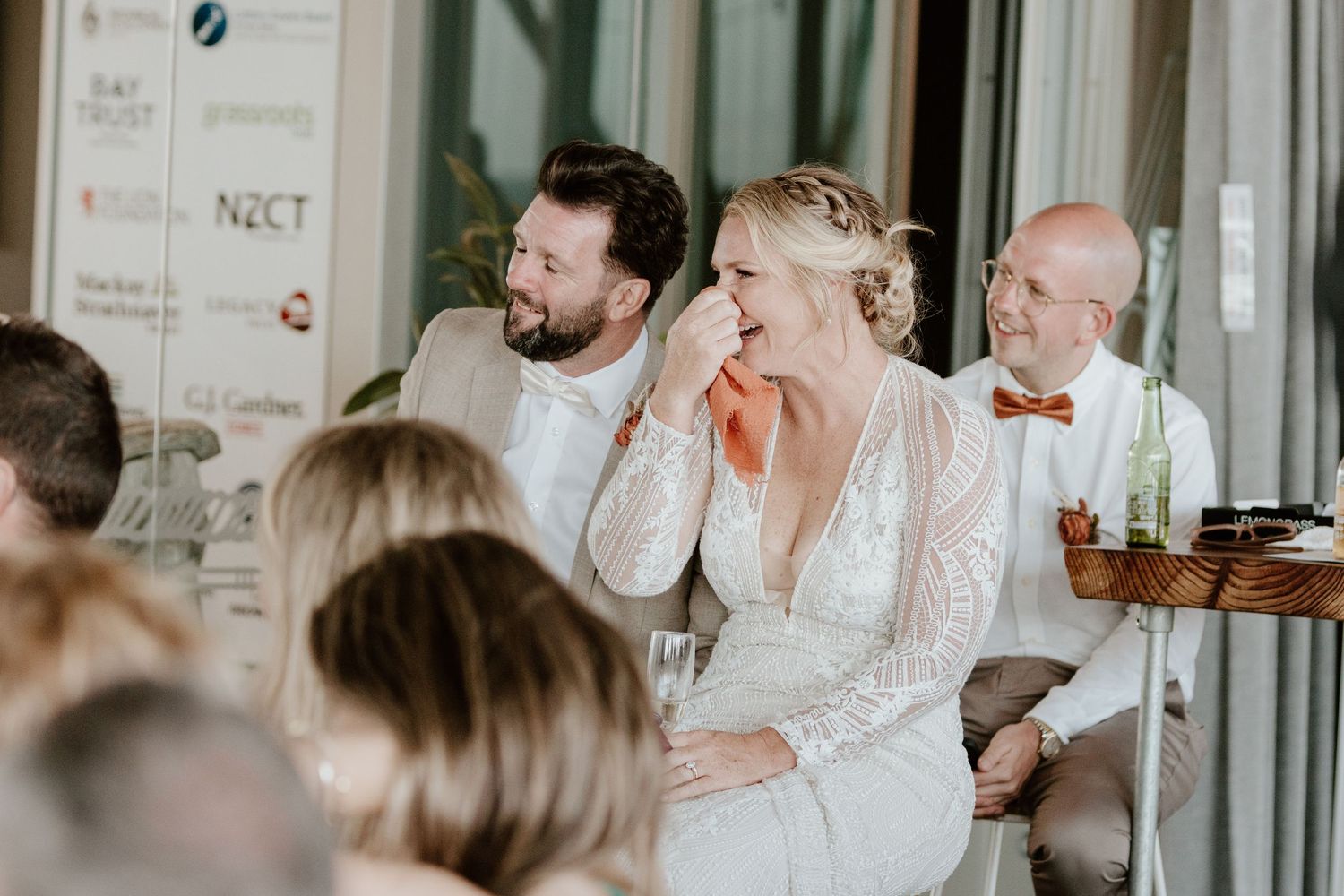 Guests at a wedding reception share joyful moments as they enjoy the celebration. Papamoa Surf Lifesaving Club Wedding