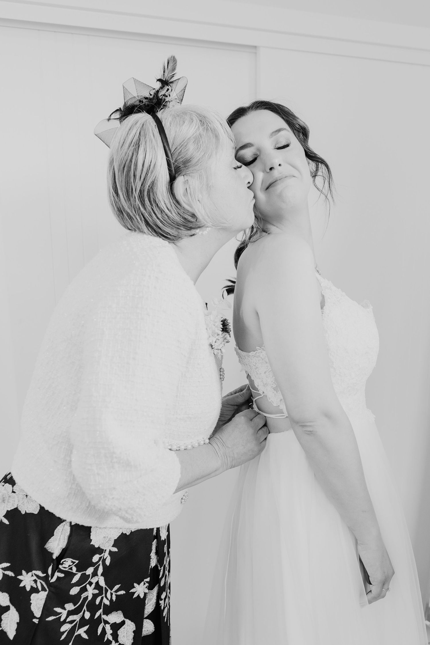 A tender black and white moment between a bride in a white dress and loved one in floral attire.