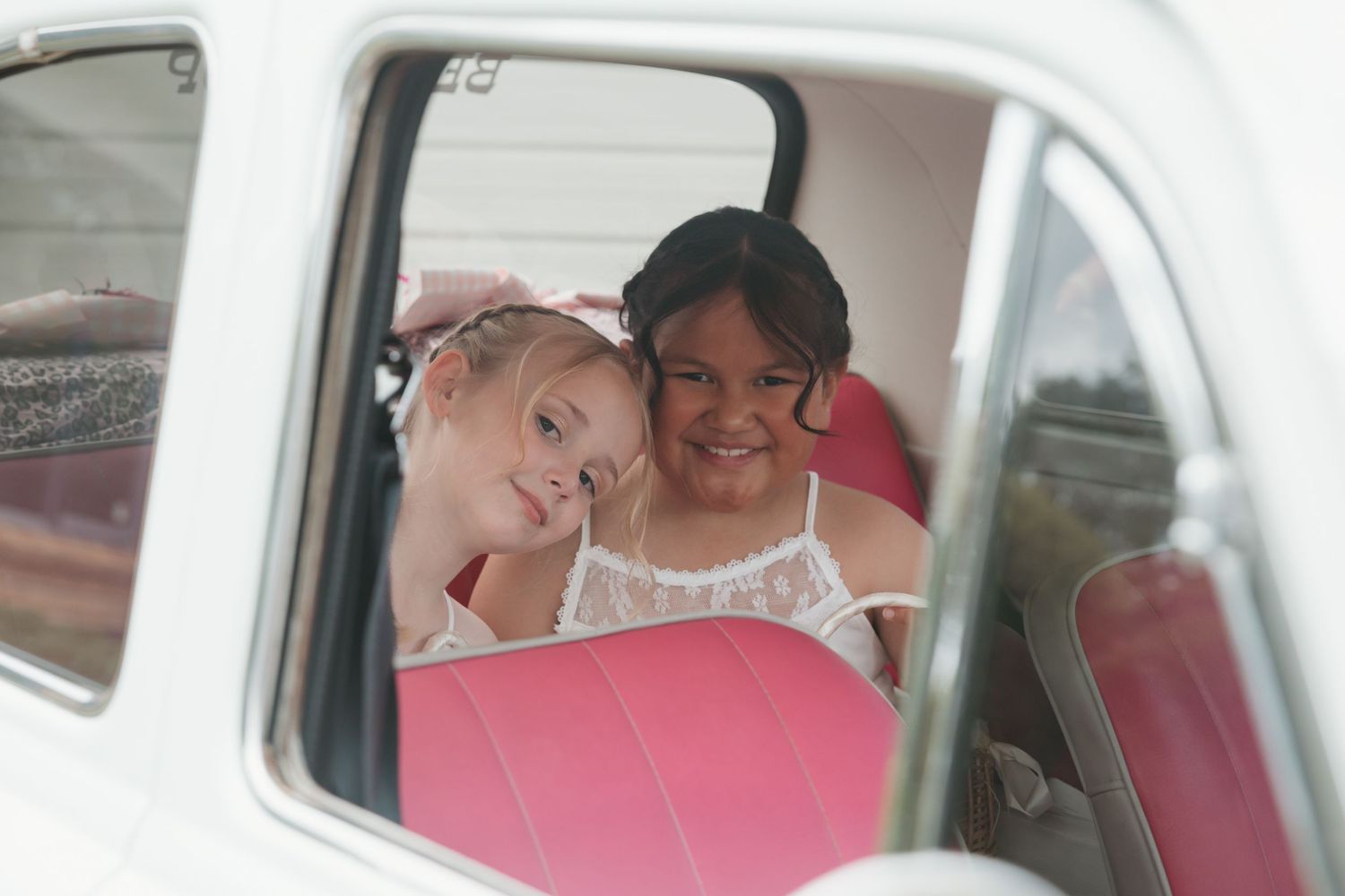 A couple shares an intimate moment in a vintage car after their wedding ceremony.