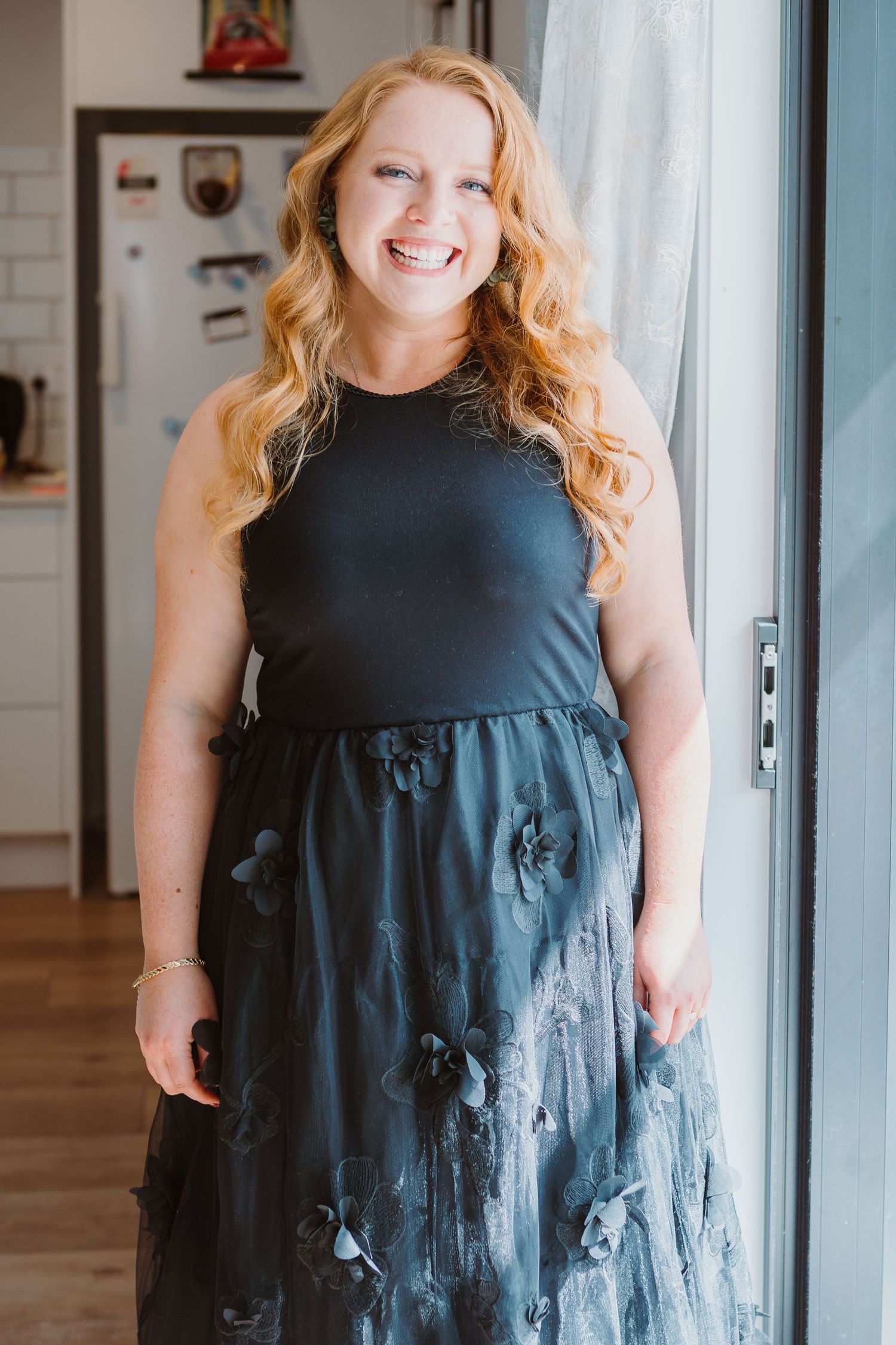 A flowing black evening dress with delicate details and ruffles shown in multiple angles.