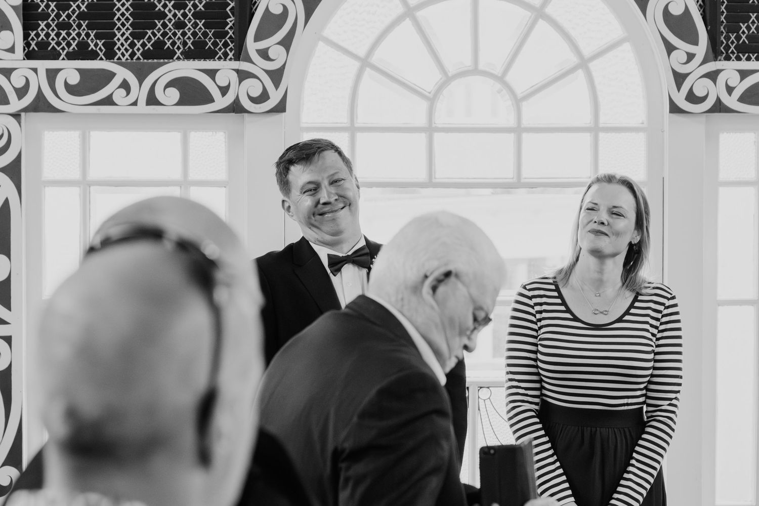 Wedding guests in formal attire gathered to celebrate at an elegant conservatory reception.