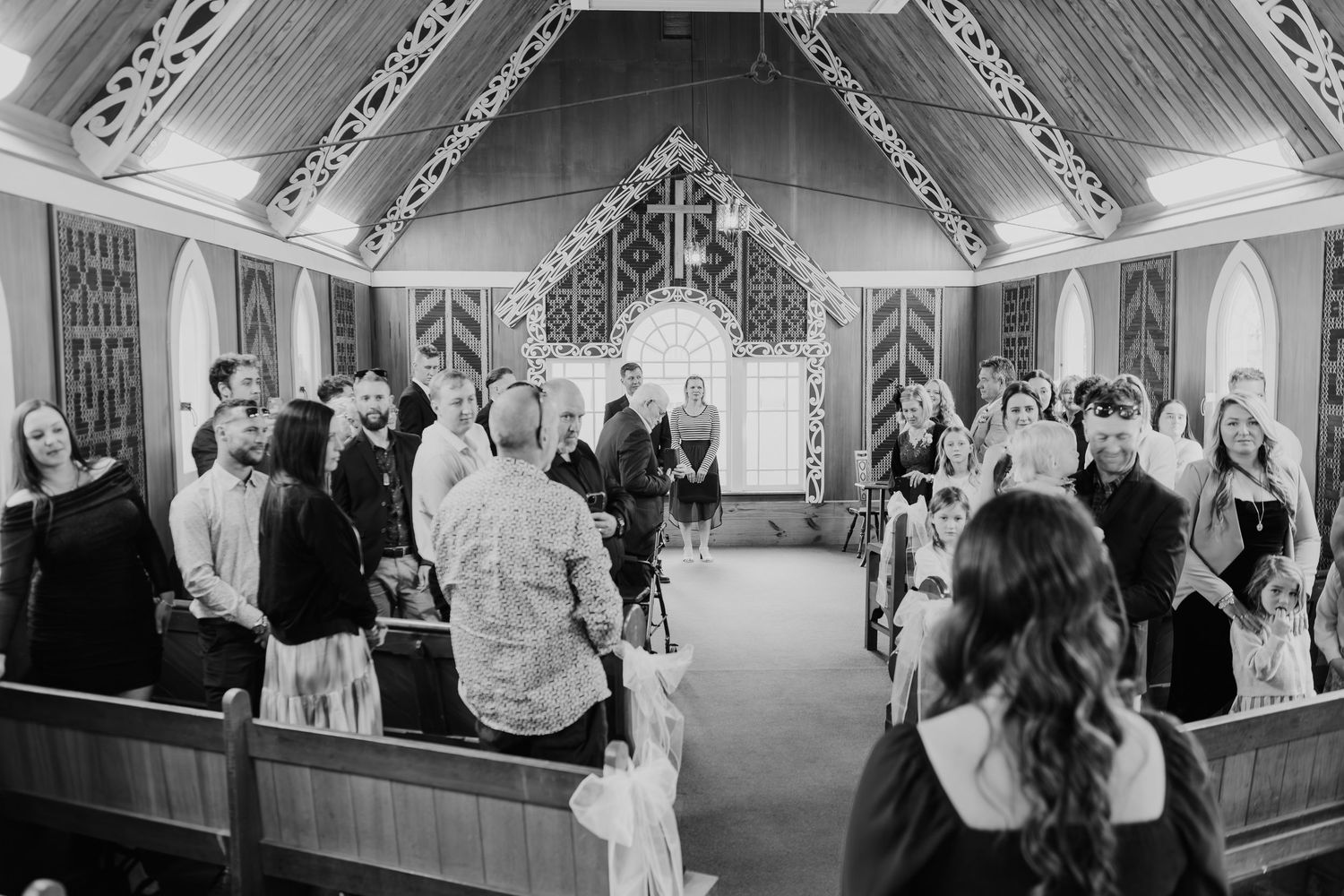 Wedding guests dance and celebrate in an elegant church hall with ornate decorative details and arched windows.