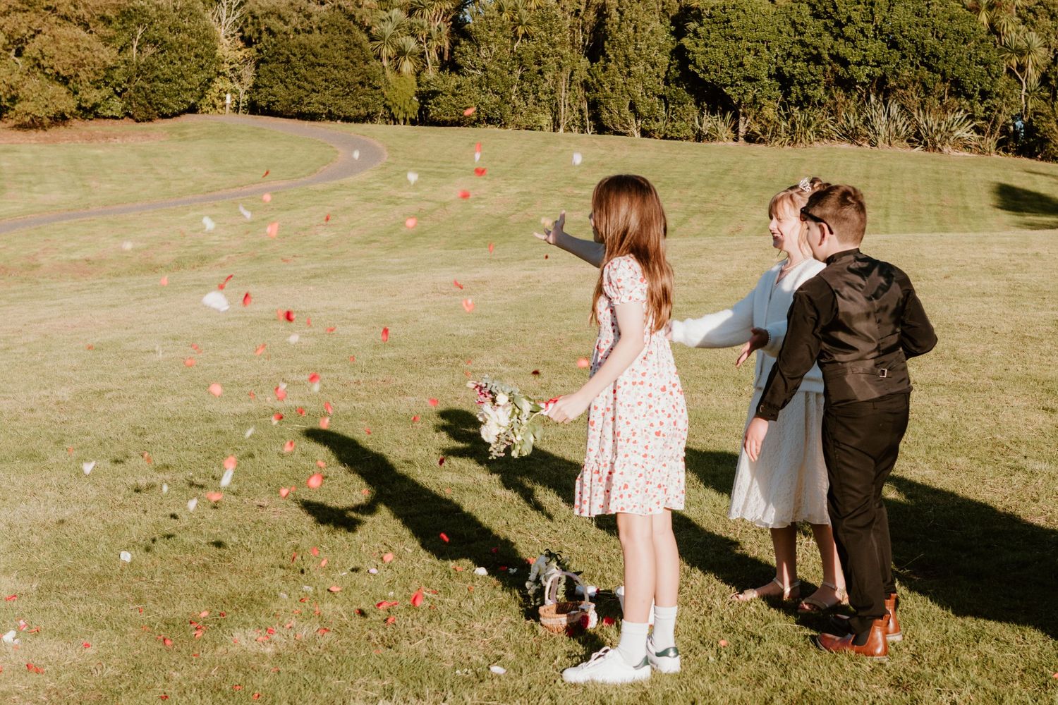 Group releasing autumn leaves into the air at a sunny park creating a joyful seasonal moment.