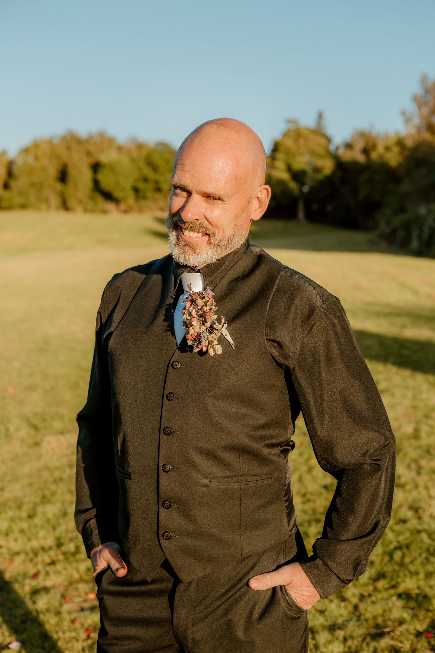 Person in olive suit jacket stands in golden sunlit field during sunset with warm autumn lighting.