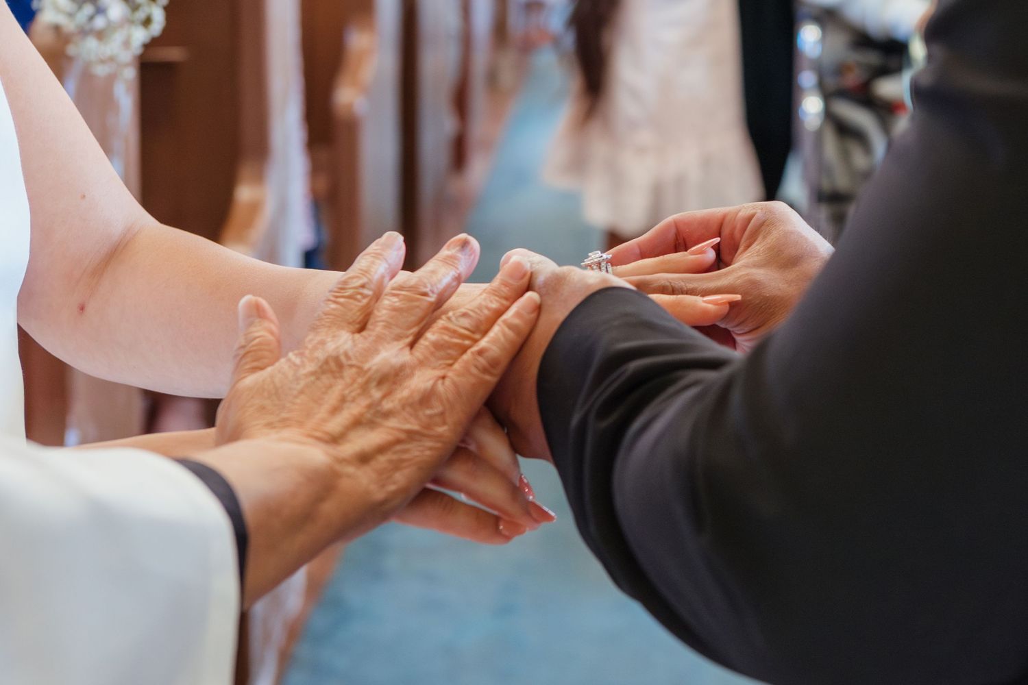 Close-up of hands during wedding ring exchange ceremony in church setting.