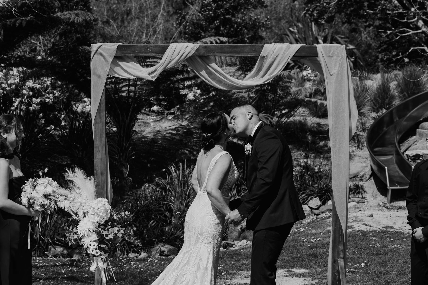 A series of black and white wedding ceremony photos showing a couple exchanging vows under an outdoor gazebo.