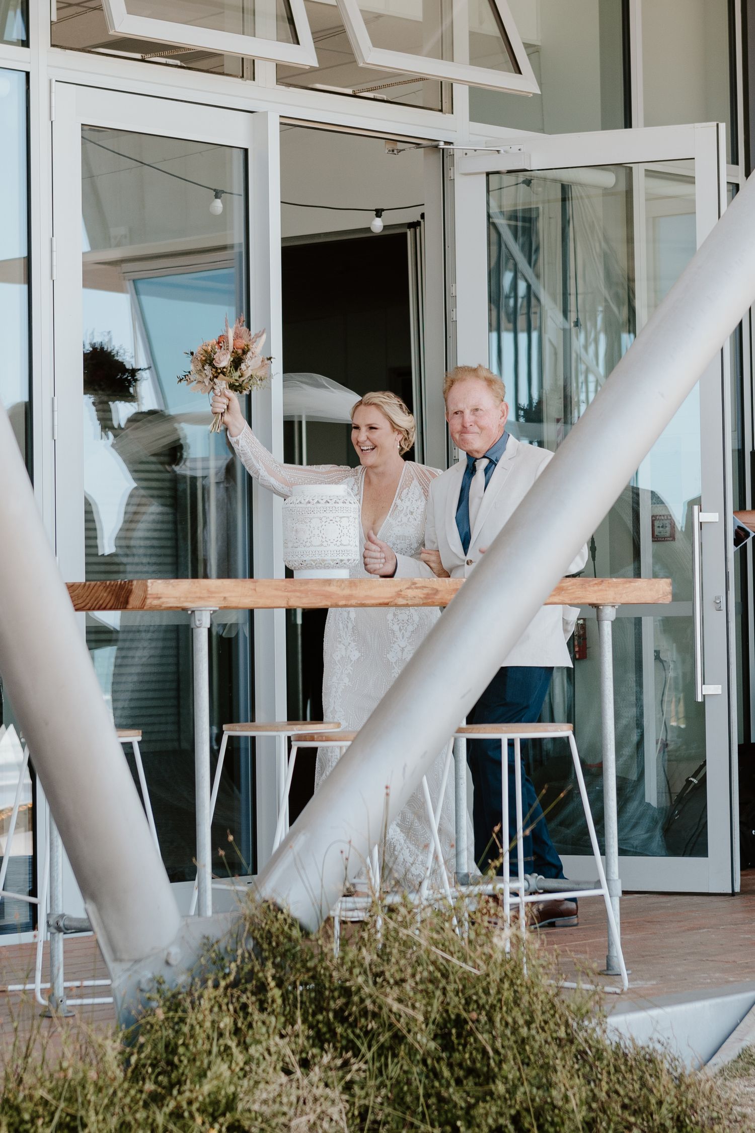 Modern beachfront venue with glass walls and coastal views hosts wedding festivities. Papamoa Surf Lifesaving Club Wedding
