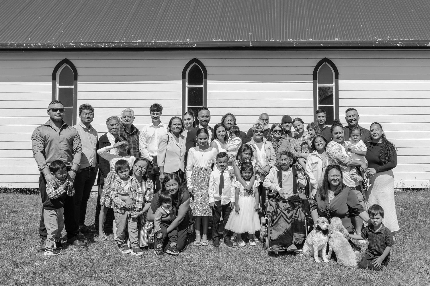 Panoramic shot of wedding guests seated in front of a white church building.