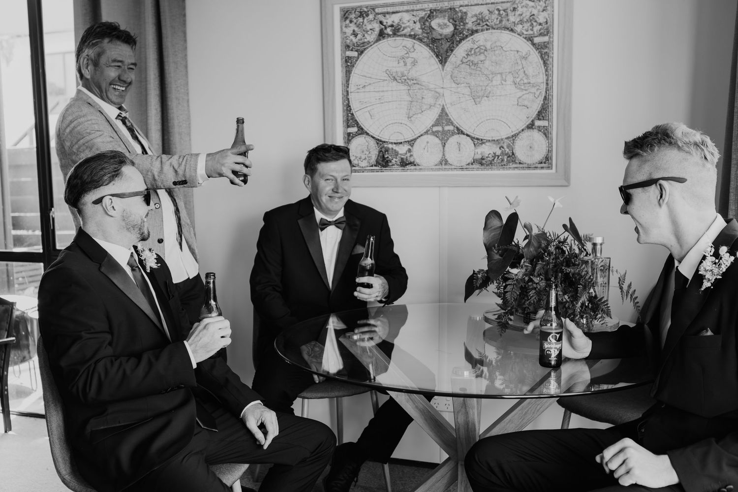 A black and white panel of images showing people in formal attire looking at maps and globes in an office setting.