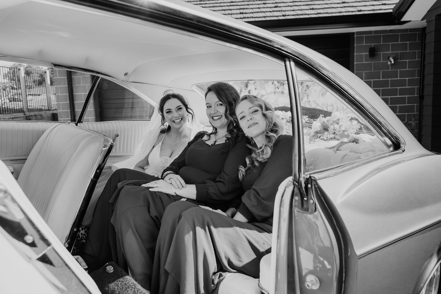 Wedding party seated in the back of a vintage car with elegant interior.