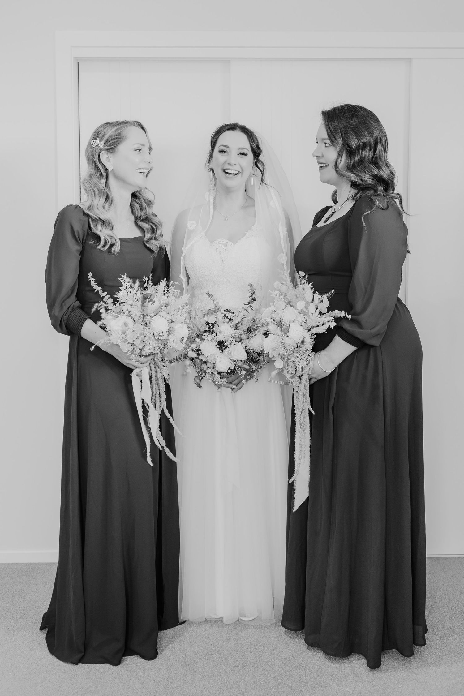 Black and white wedding photo series showing bridesmaids in dark dresses gathered around bride in white gown with bouquets.