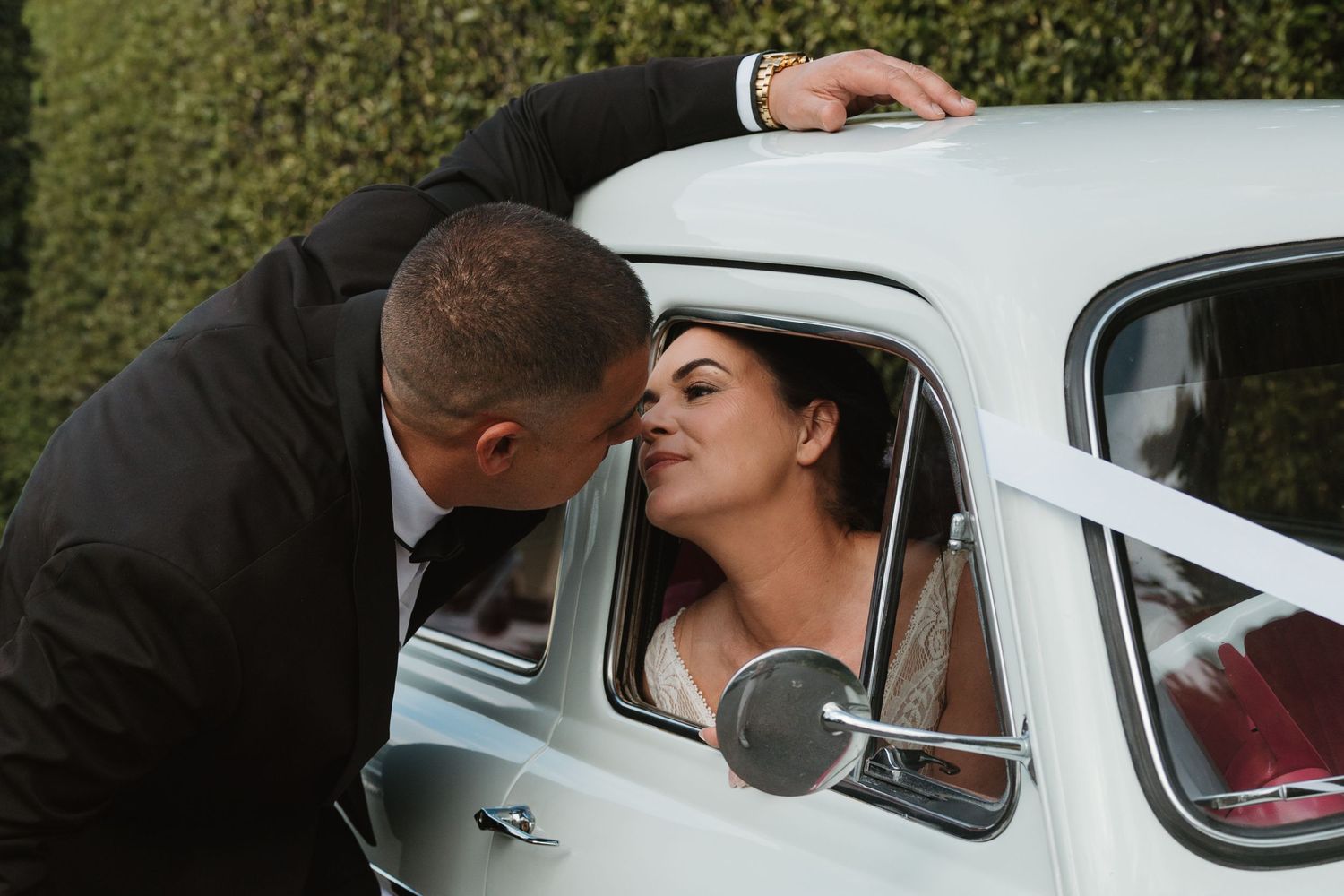 A series of wedding photos showing a couple sharing intimate moments in and around a white vintage car.