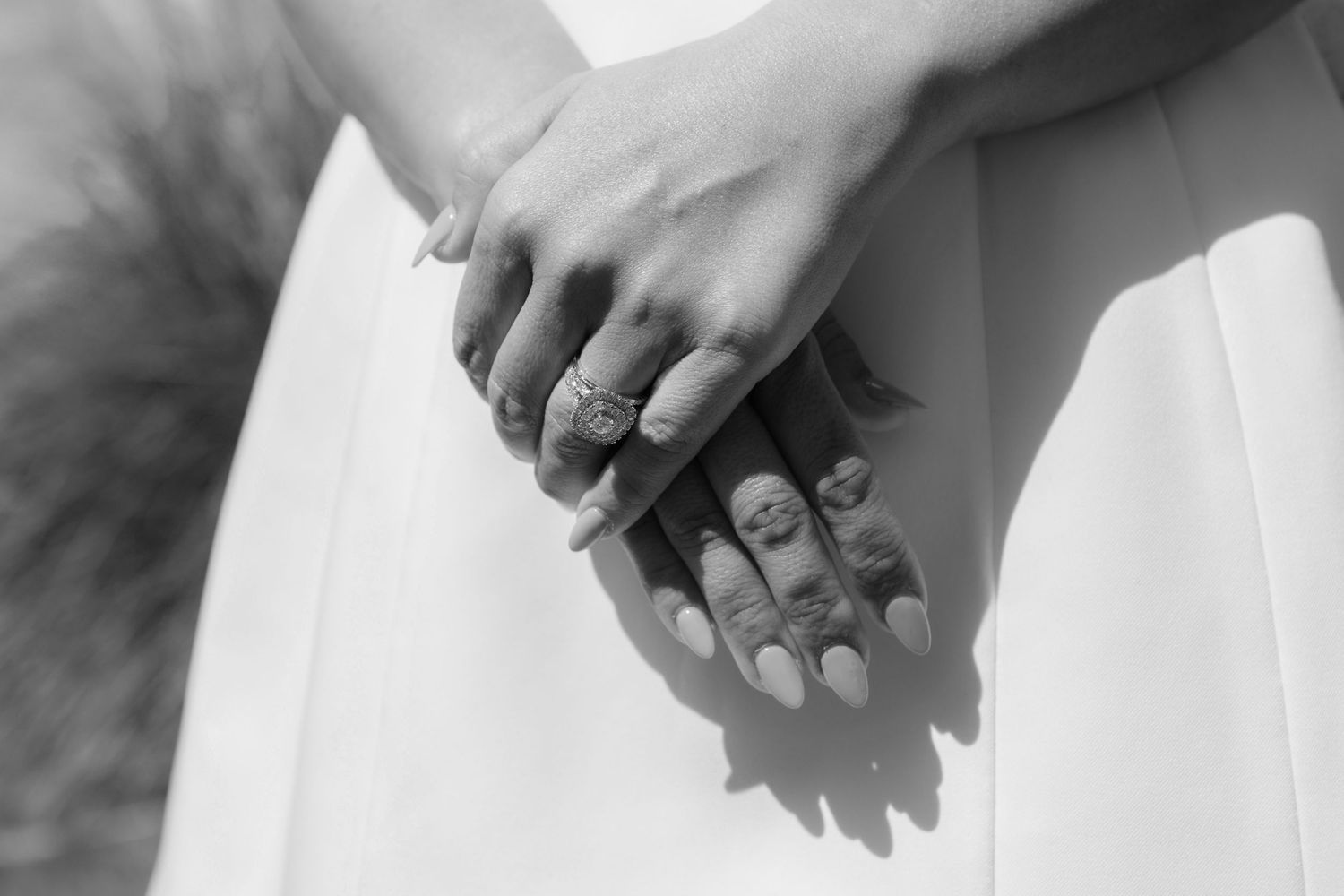 Close-up black and white photo of hands with wedding rings creating shadows.