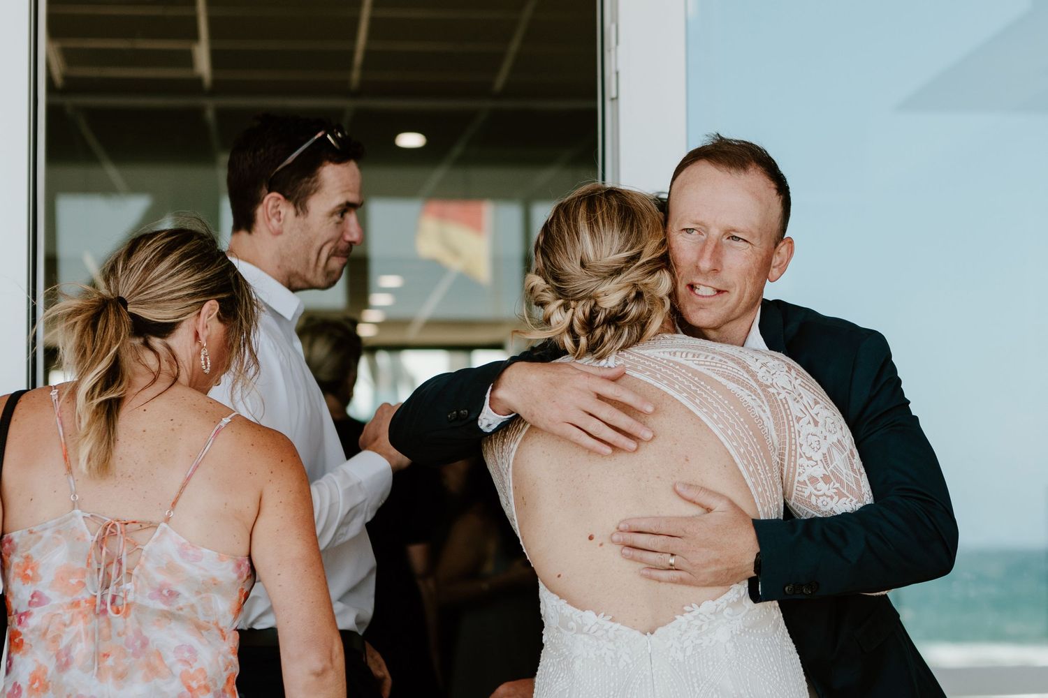 Wedding party members sharing joyful moments during indoor celebration. Papamoa Surf Lifesaving Club Wedding