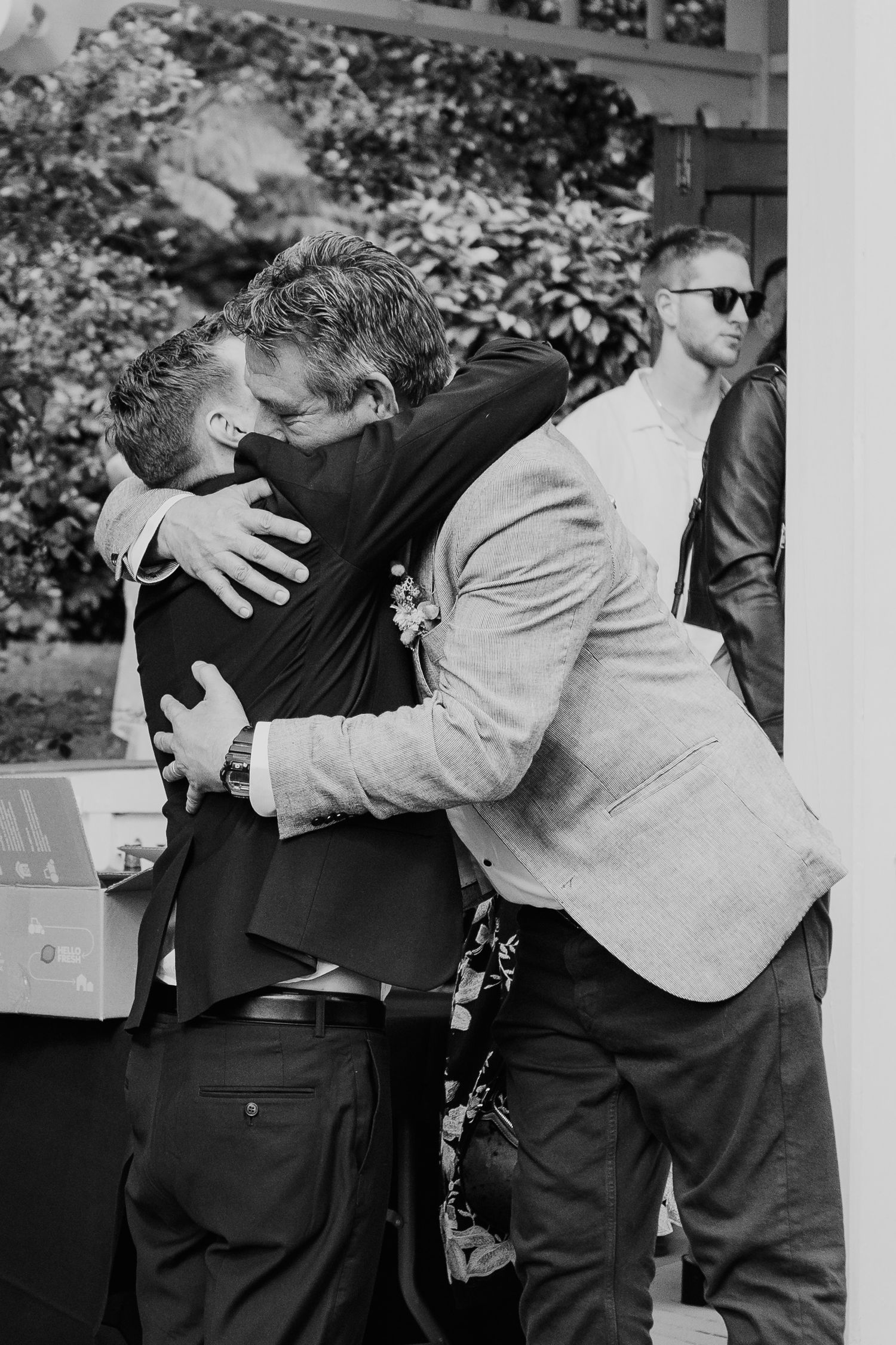 Black and white sequence of photos showing two people sharing a warm embrace at a formal event.