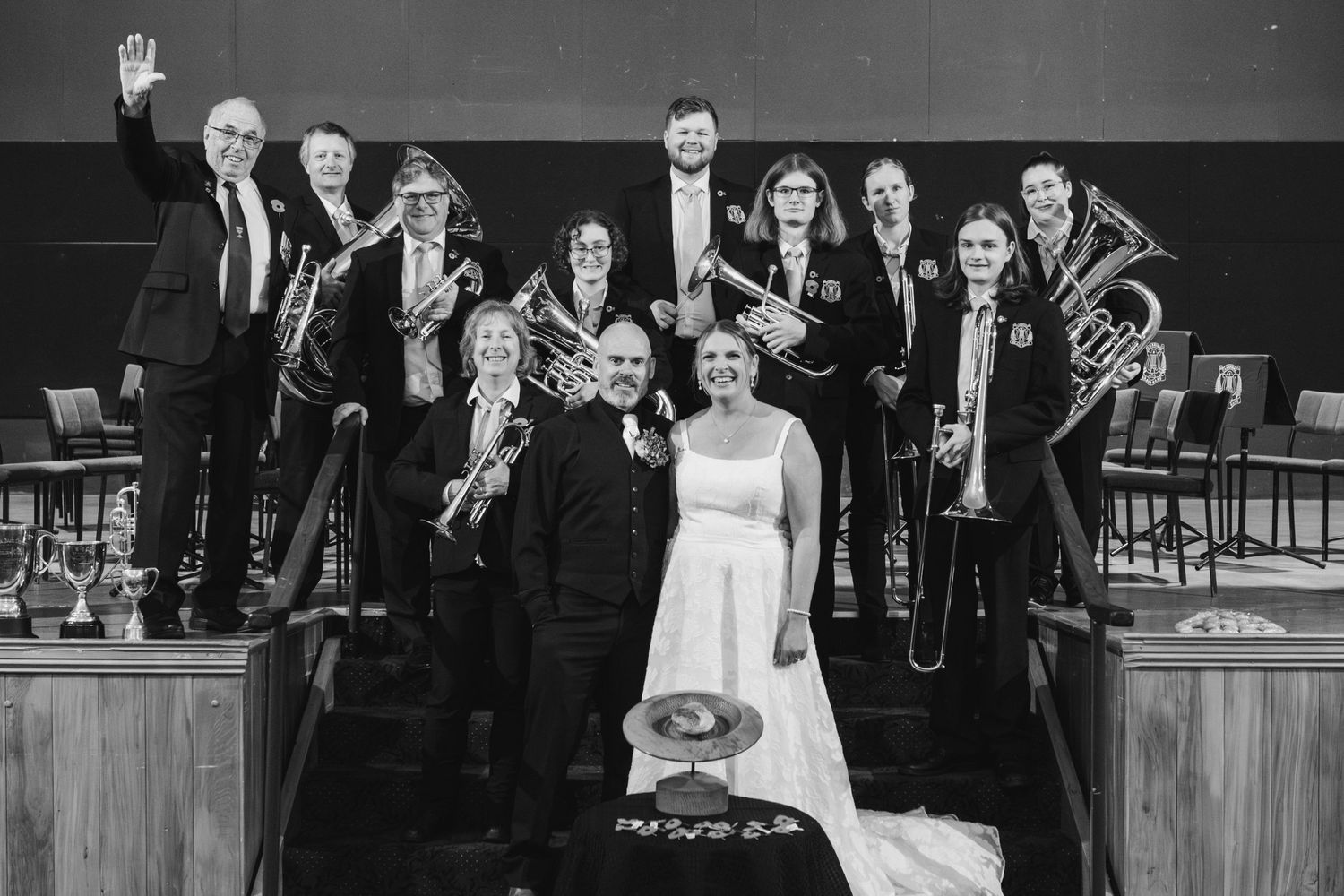 A black and white photo of a musical ensemble with brass instruments and a person in a white dress on stage.