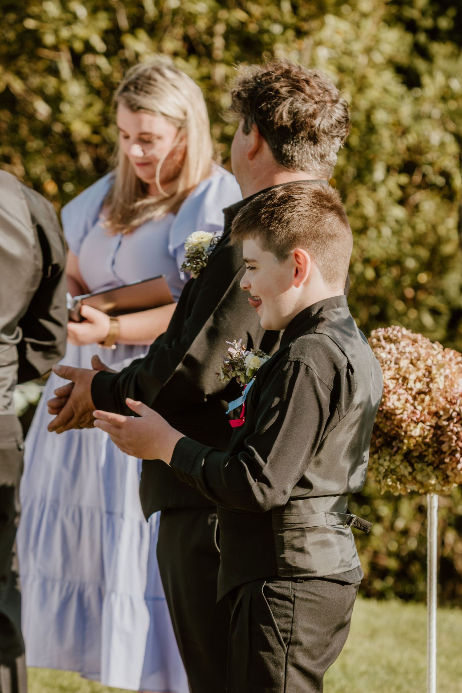 Emotional candid reaction captured at an outdoor wedding ceremony in a garden setting with natural sunlight.