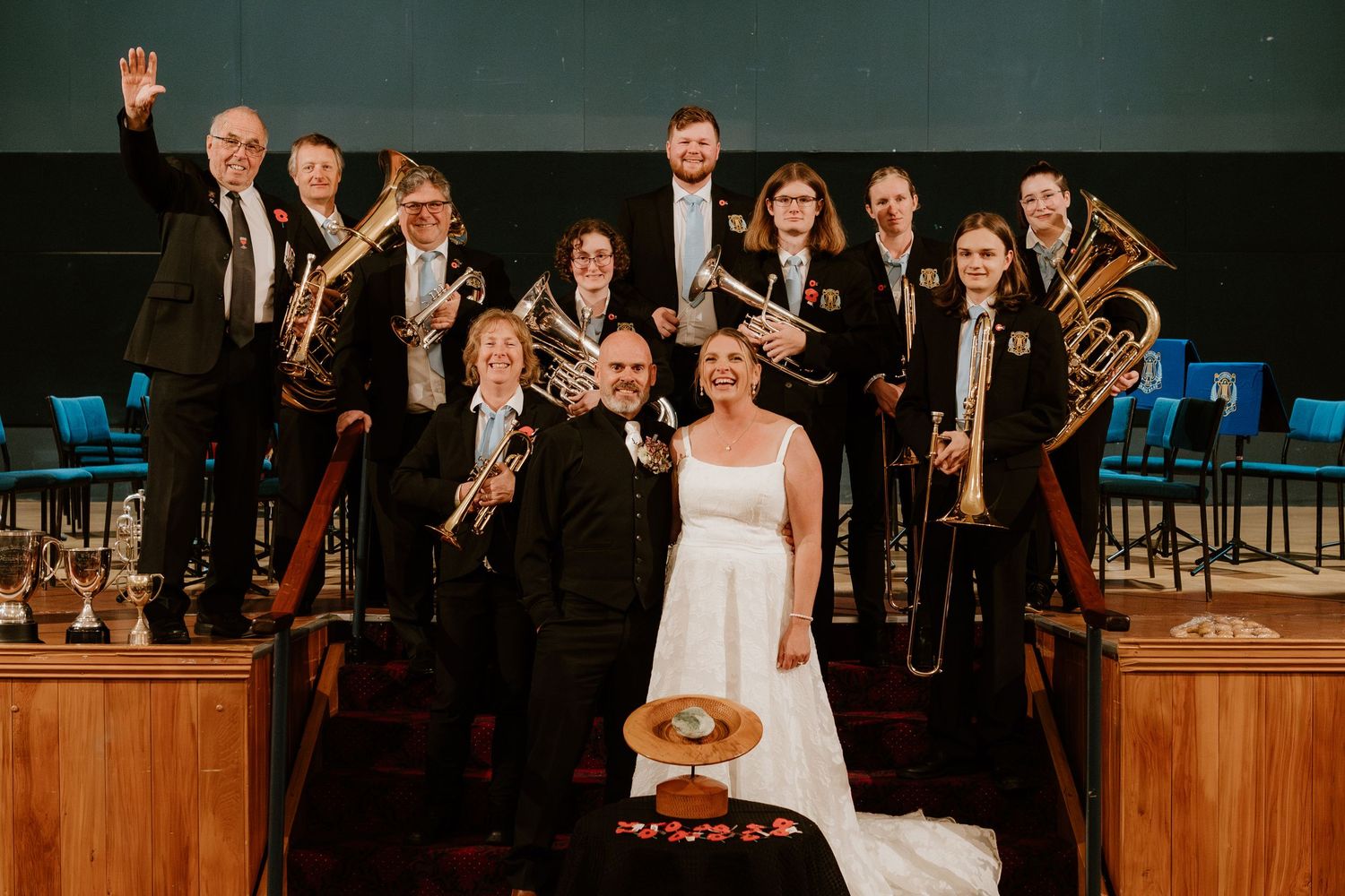 Musicians in formal attire gather on stage with musical instruments for a wedding performance.