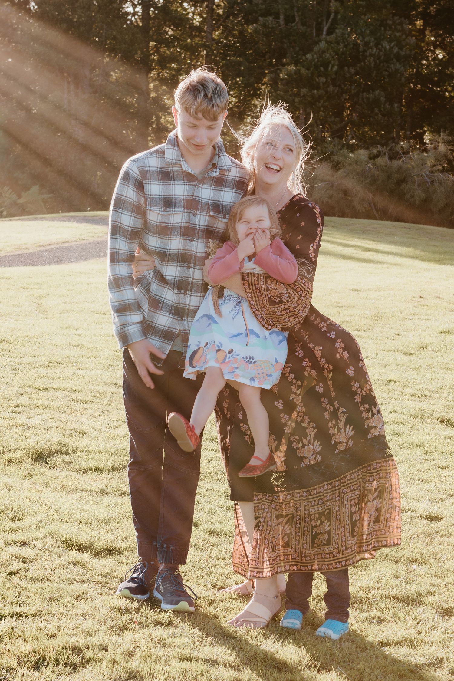 Family enjoys golden hour sunlight while playing together in a grassy park on a warm afternoon.