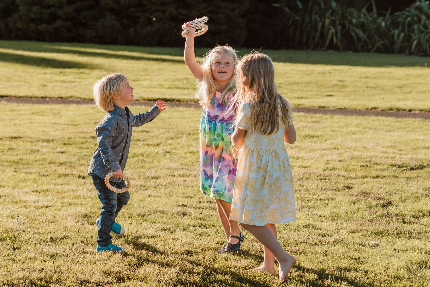Children playing and dancing together in a grassy field at sunset during a fun outdoor activity.