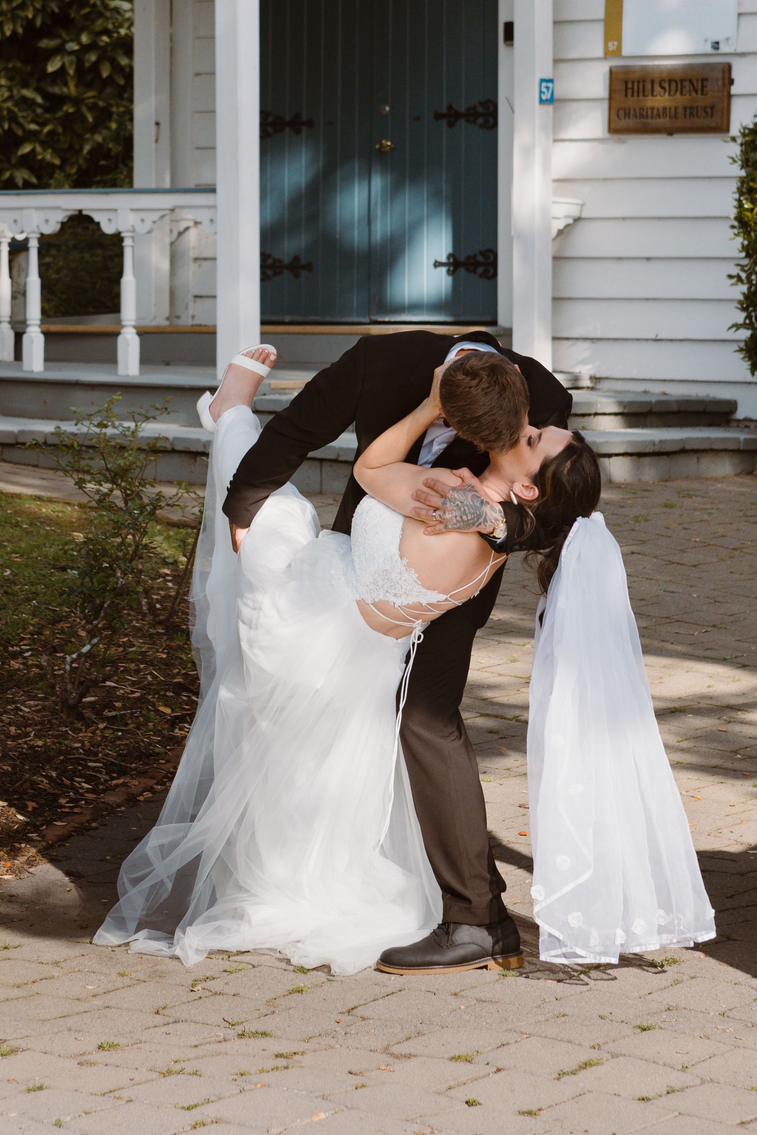 A romantic dip pose sequence showing a couple during their wedding photo session on a stone patio near white columns.