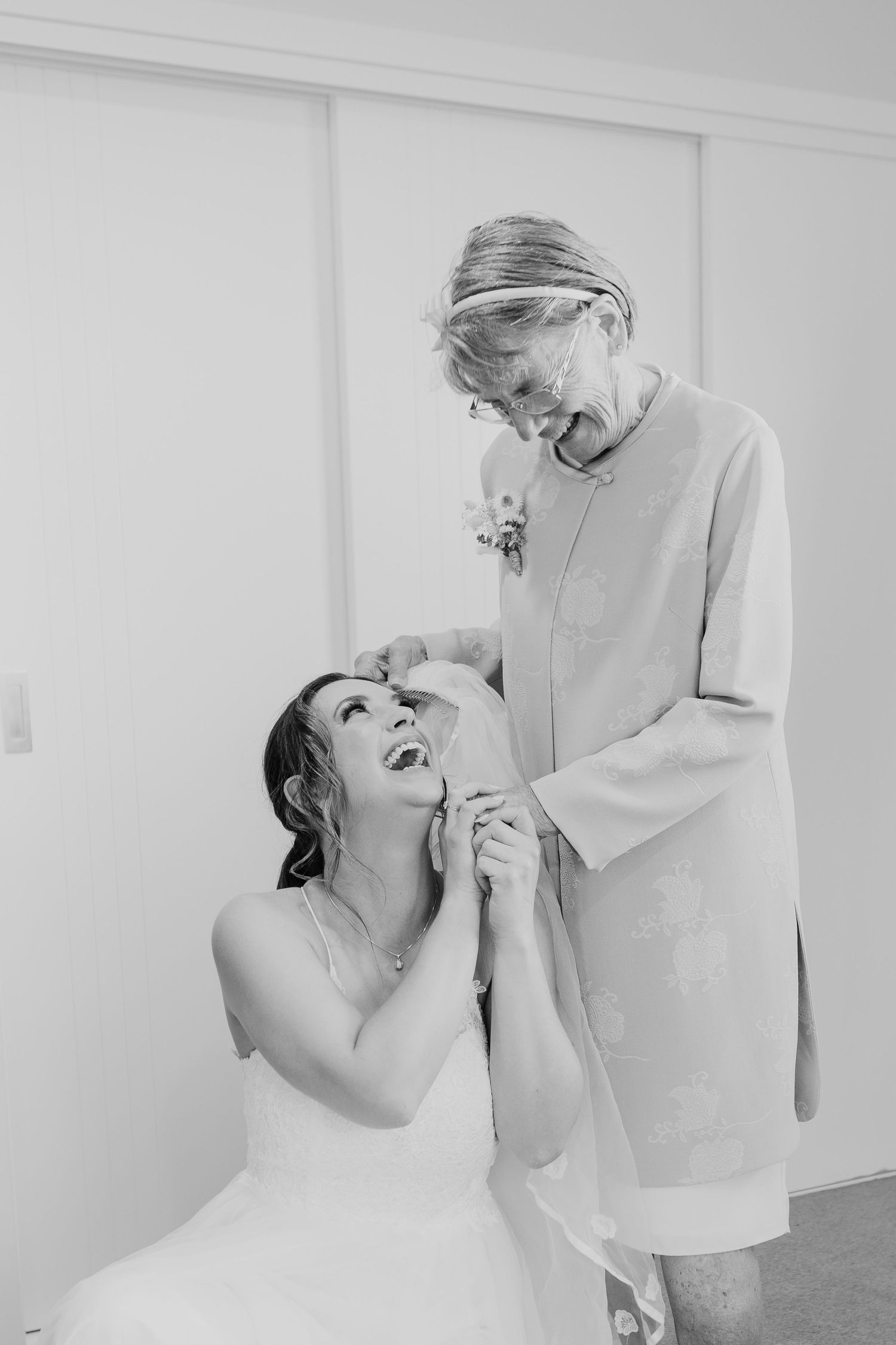 A heartwarming black and white candid moment shared between a bride in white and loved one before the wedding ceremony.