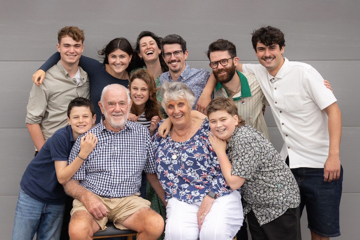 A group of people posing together in casual attire against a gray background in multiple connected photos.