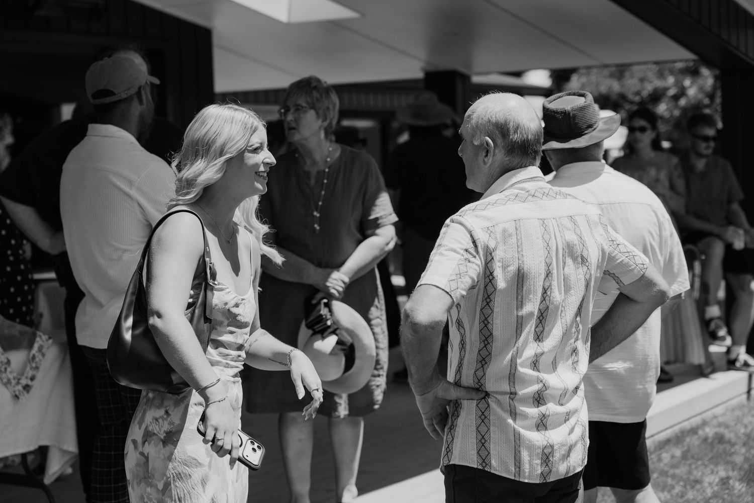 Black and white photo of guests socializing outdoors at a casual summer gathering or garden party event.