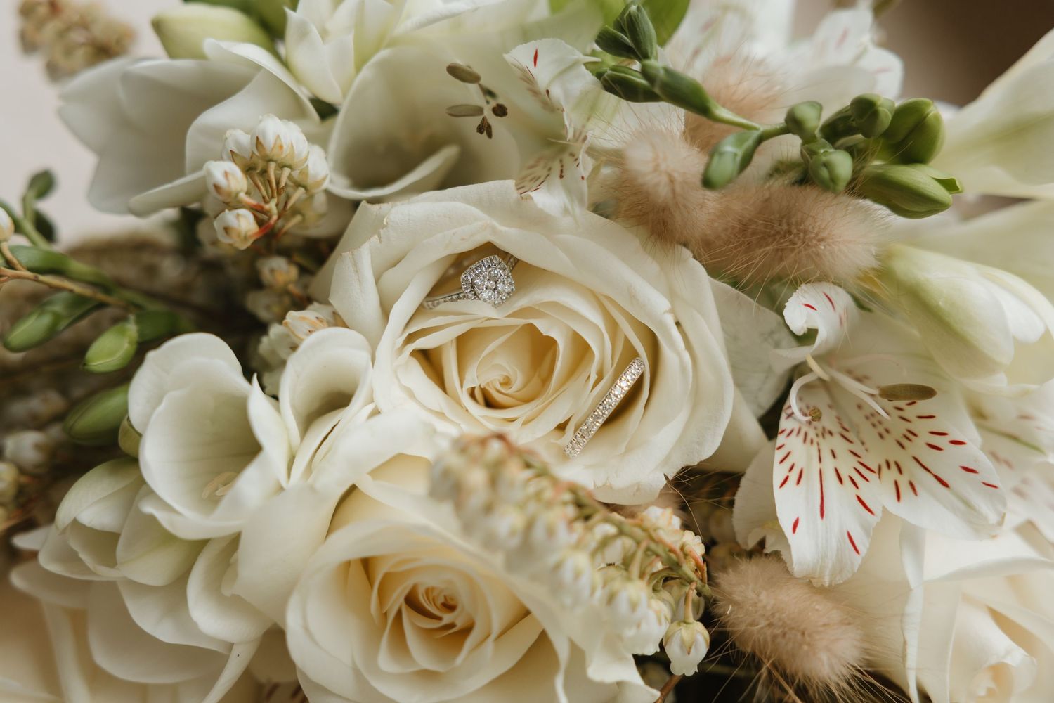 A close-up view of cream-colored roses and delicate floral arrangements with soft green foliage accents.