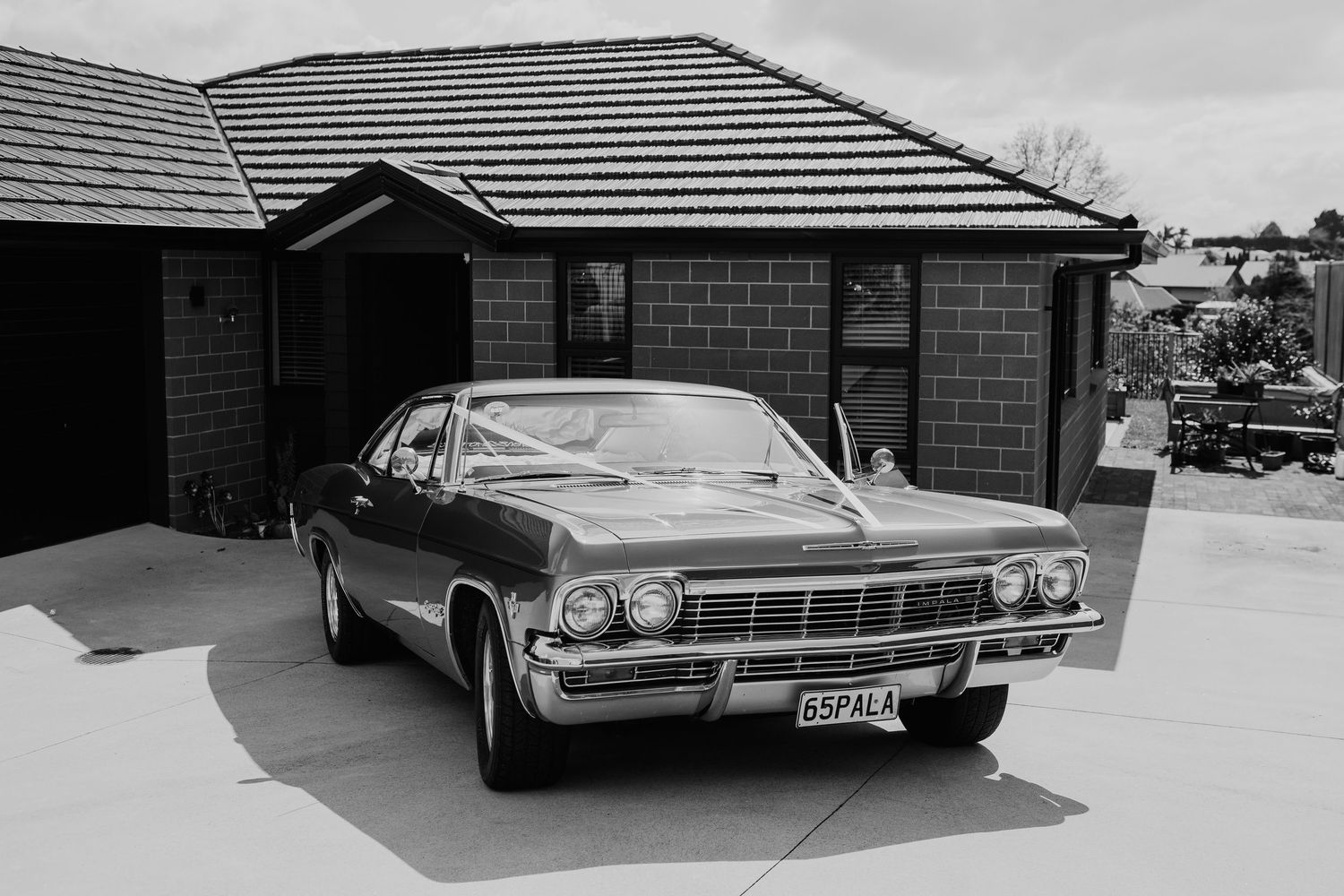 A classic vintage Chevrolet Impala parked in front of a residential house.