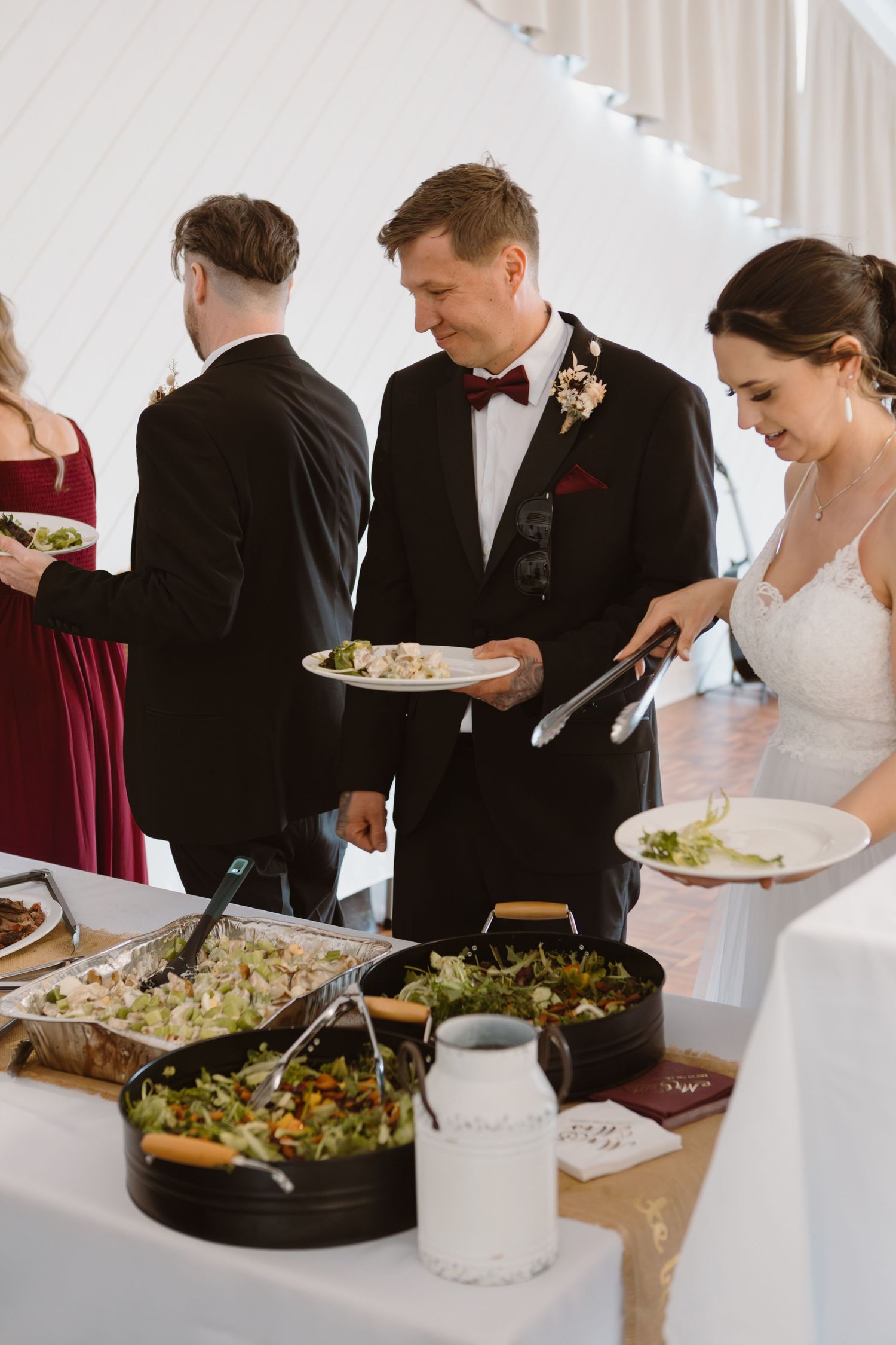Wedding reception buffet line with guests serving food from various dishes.
