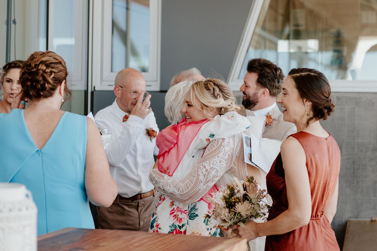 Elegant wedding scene in a bright interior venue with people gathering and celebrating in formal attire.