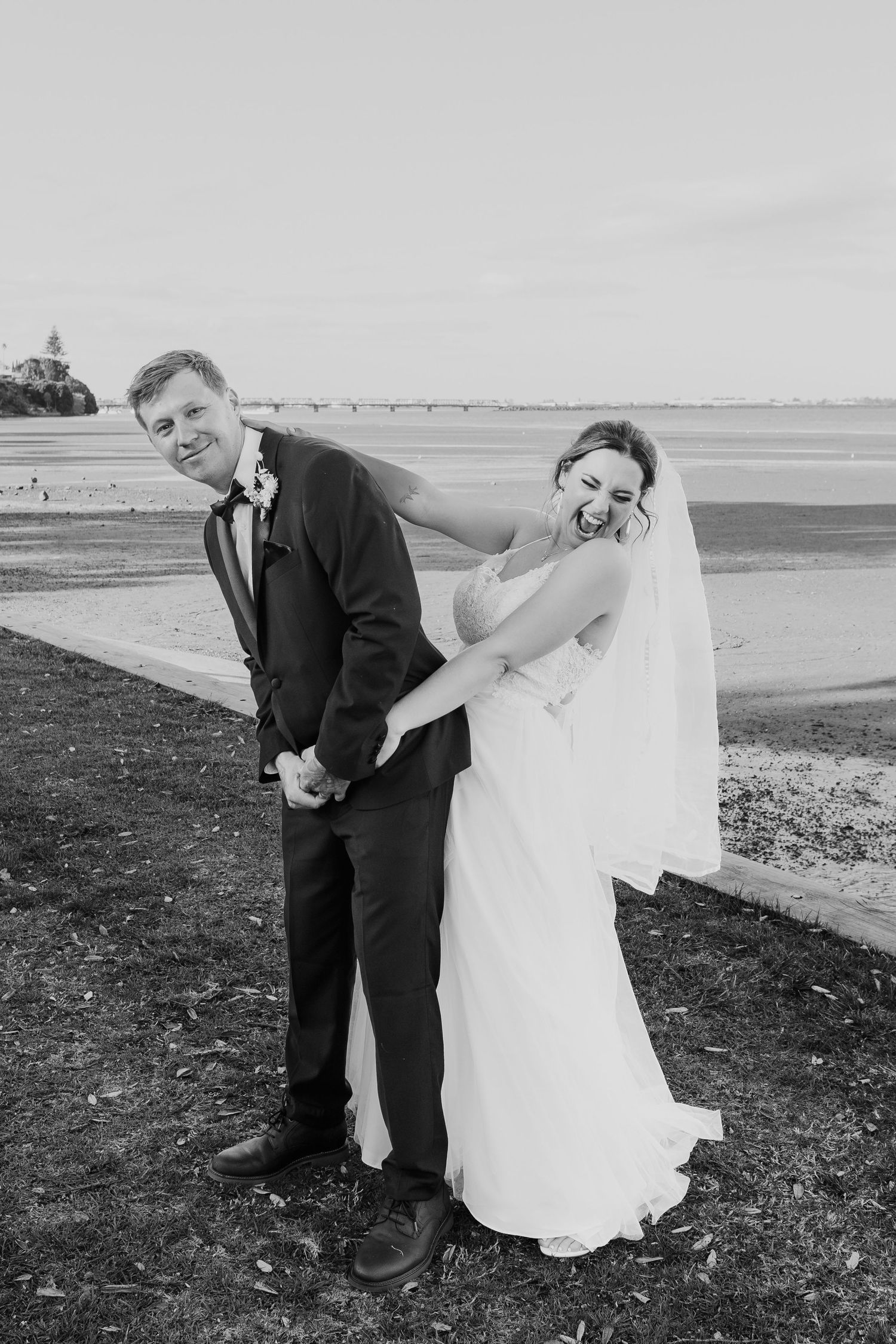 Playful wedding couple shares a candid moment in black and white photography.