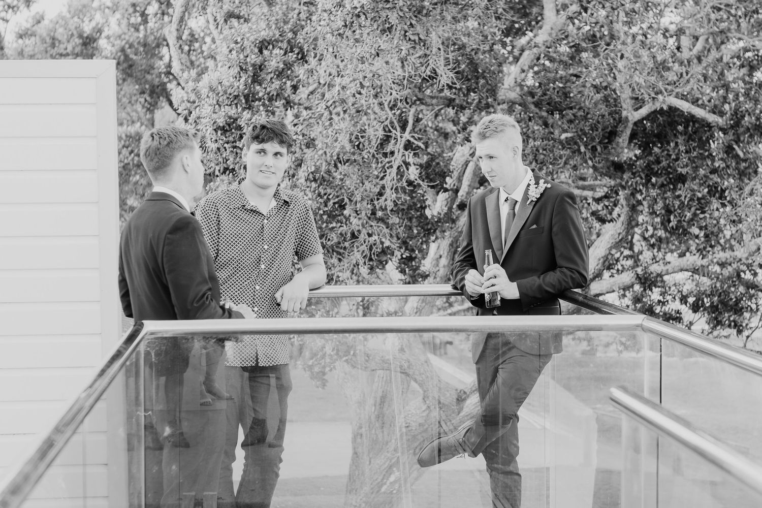 Black and white photo of formal event guests conversing on an outdoor balcony or terrace.