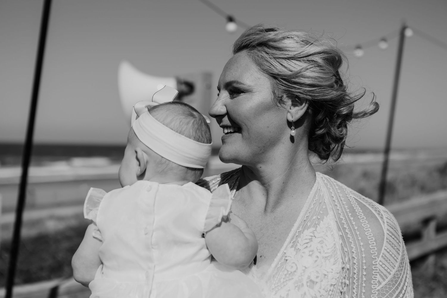 A tender moment shared between figures during a beach wedding with the ocean in the background.  Papamoa Surf Lifesaving Club Wedding