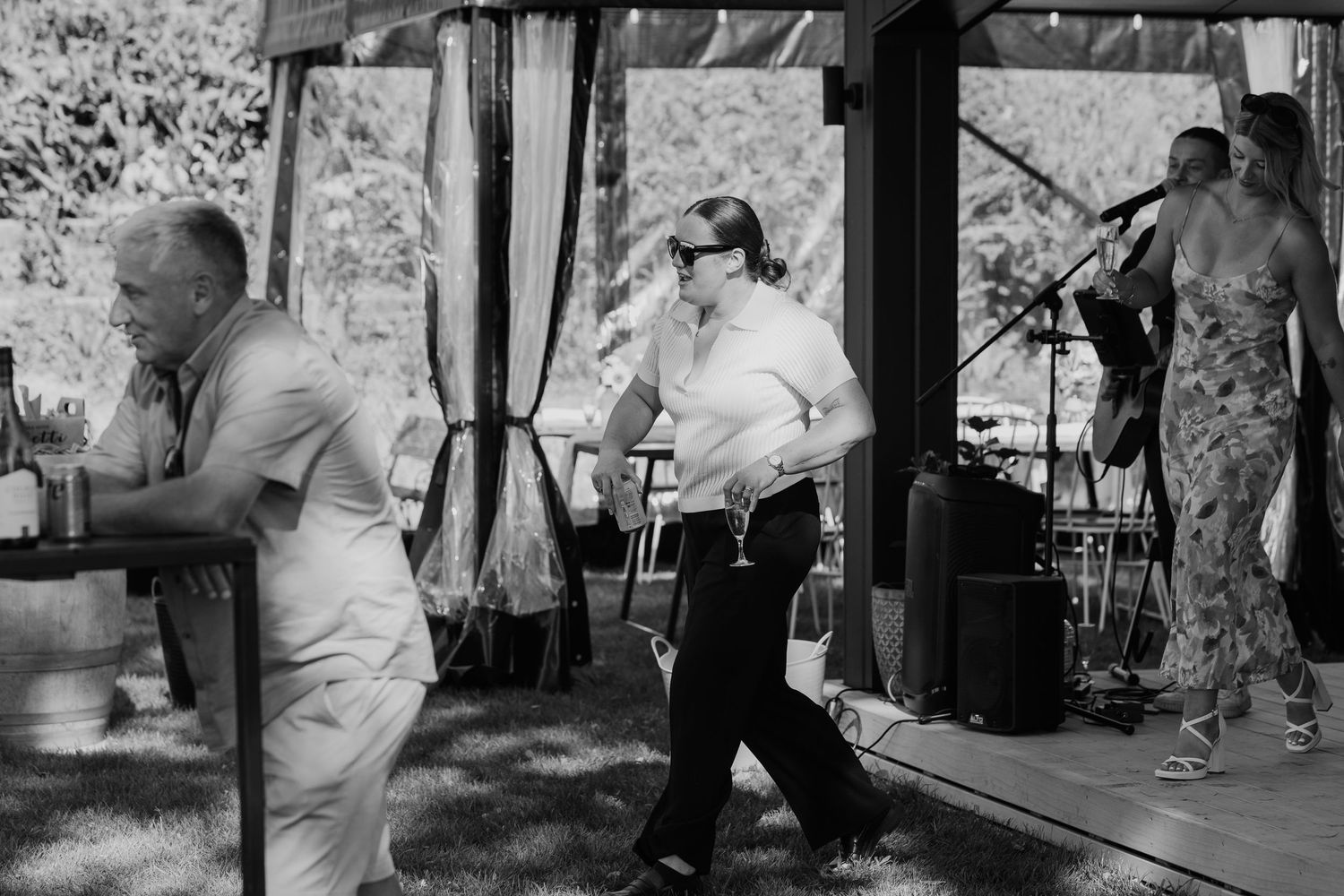 Black and white photo of guests dancing and a live band performing at an outdoor wedding reception.