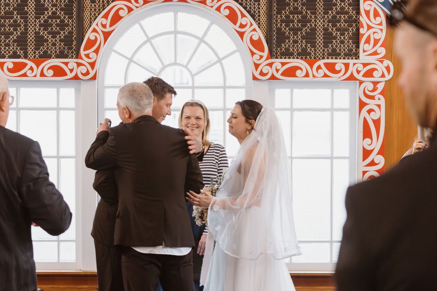 Formal reception scene showing groups of people mingling and interacting in an elegant room with ornate details and windows.