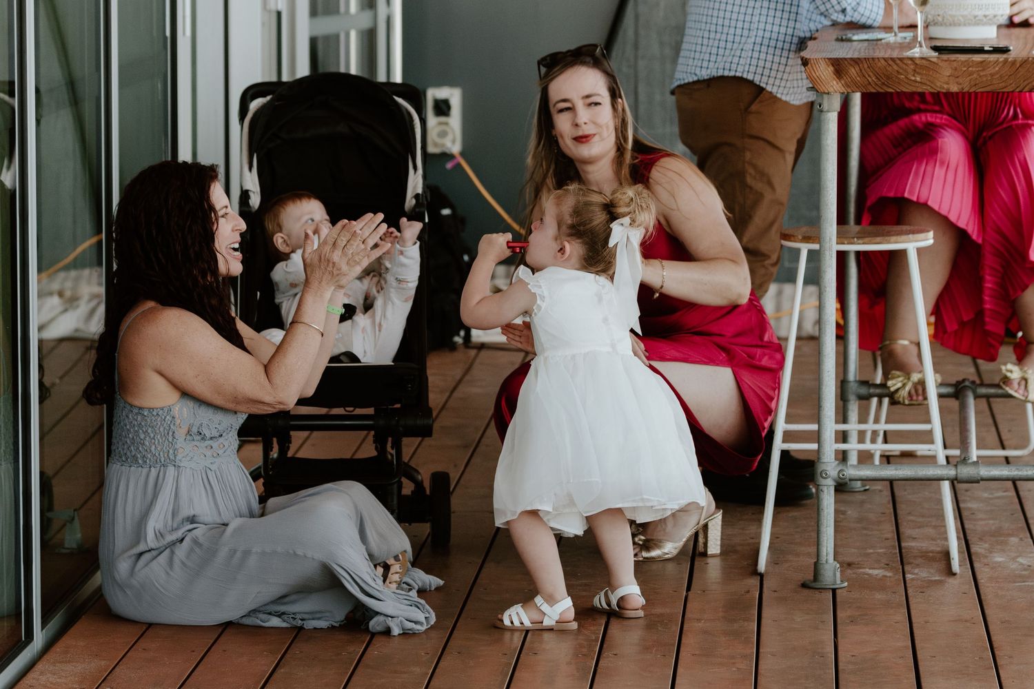 Wedding guests seated at tables on an outdoor deck enjoying the celebration. Papamoa Surf Lifesaving Club Wedding
