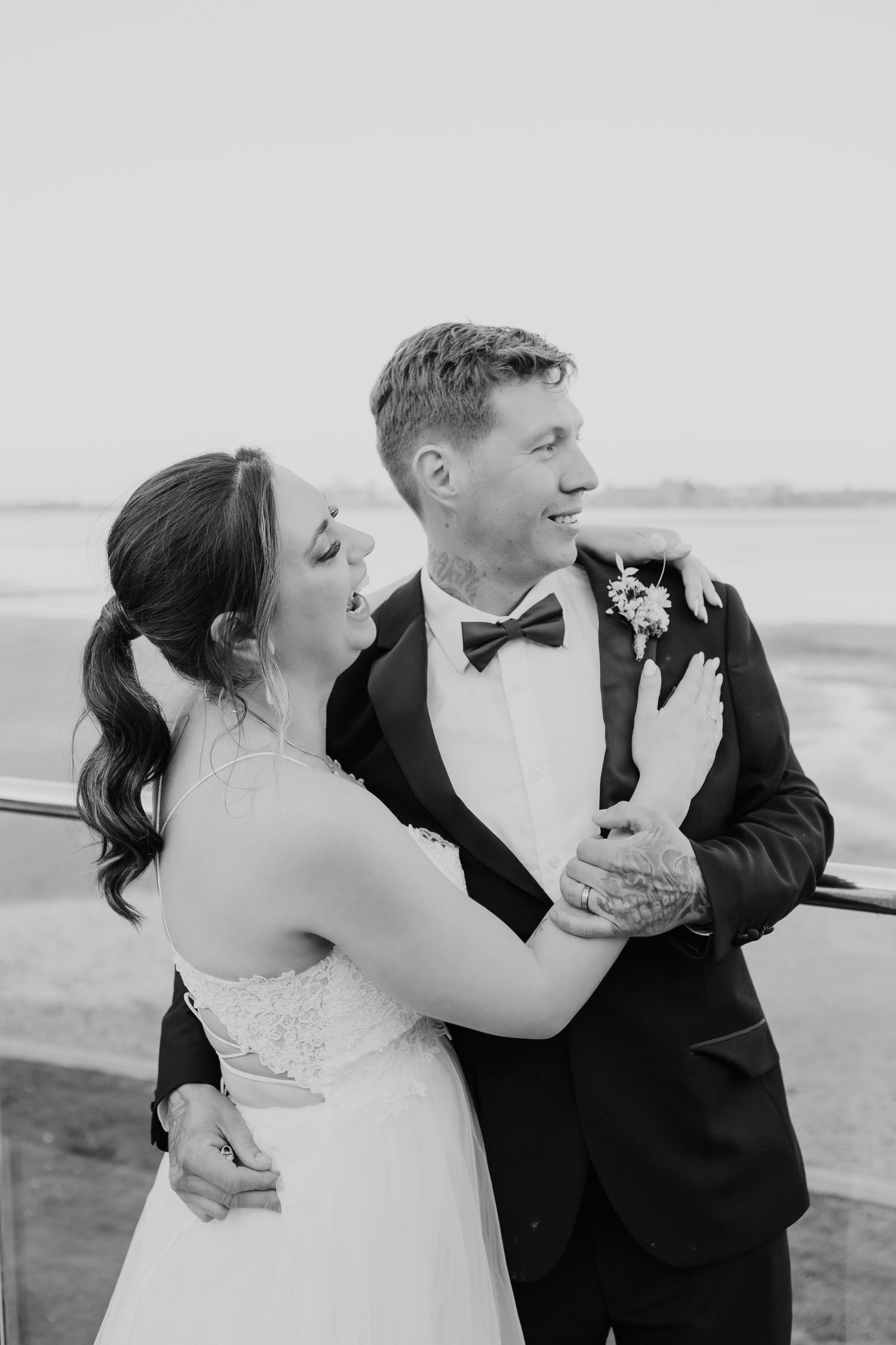 Joyful wedding couple sharing candid moment and laughter on outdoor terrace.